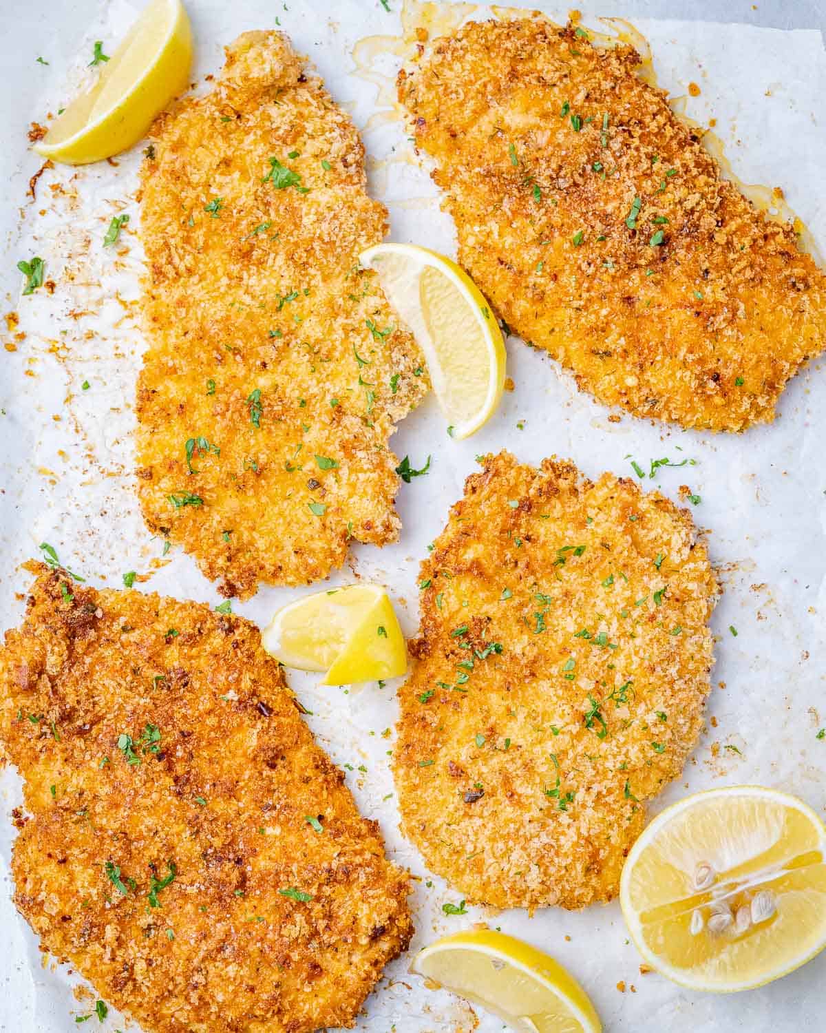 top view of parmesan baked chicken breasts with lemon wedges