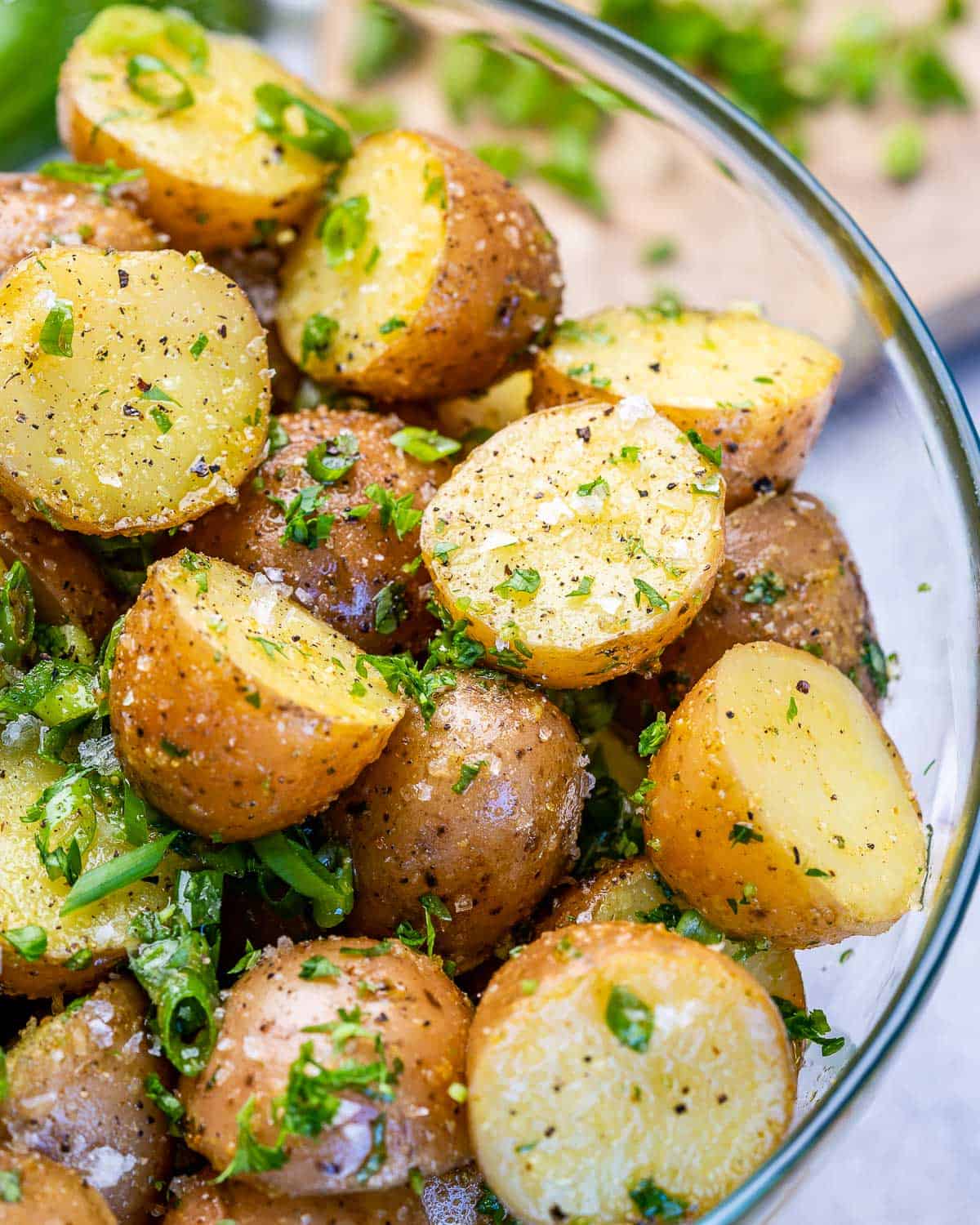 close view of cooked potatoes with herbs, salt, seasoning, green onions