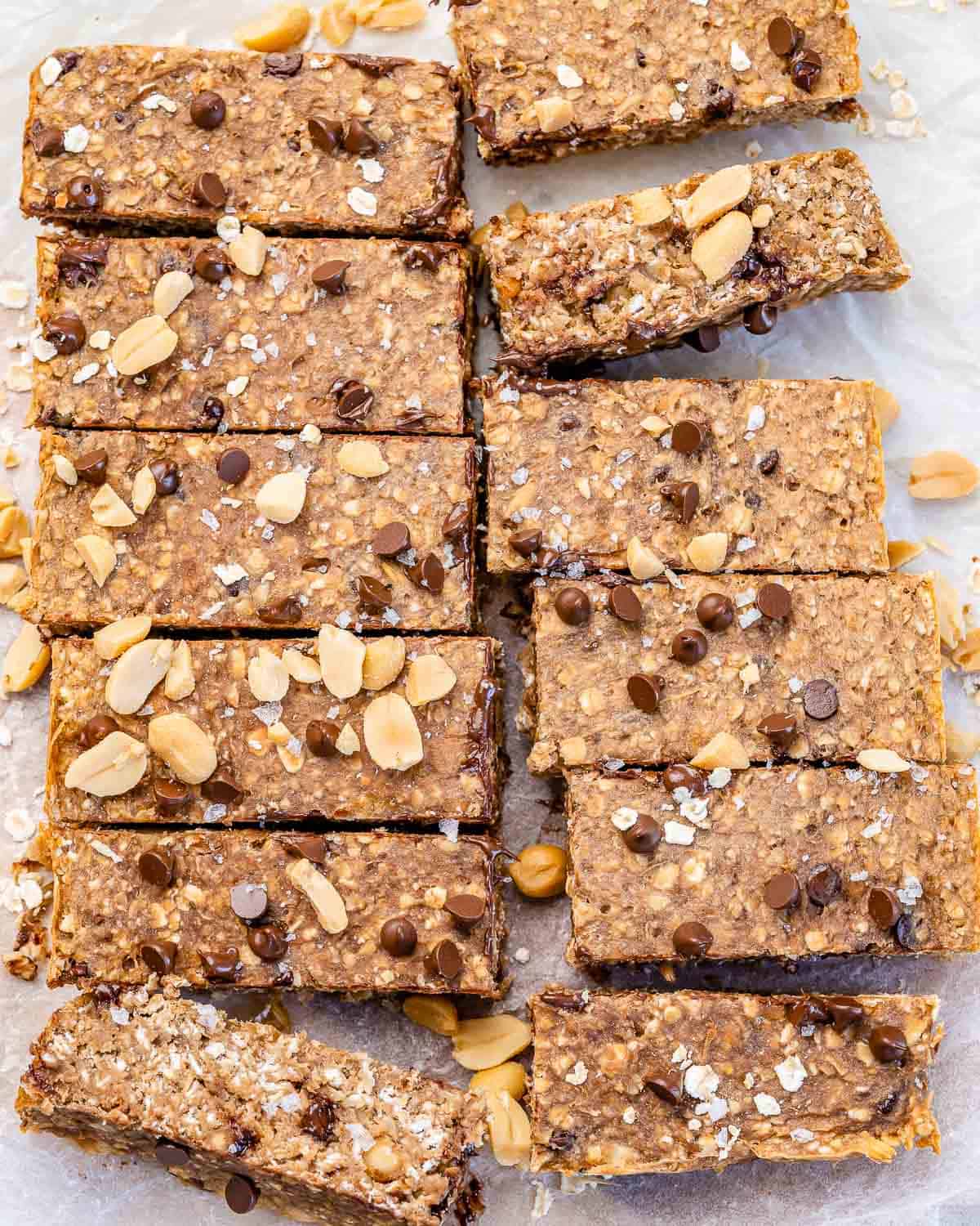 twelve chewy oatmeal bars with peanuts and chocolate chips on parchment paper