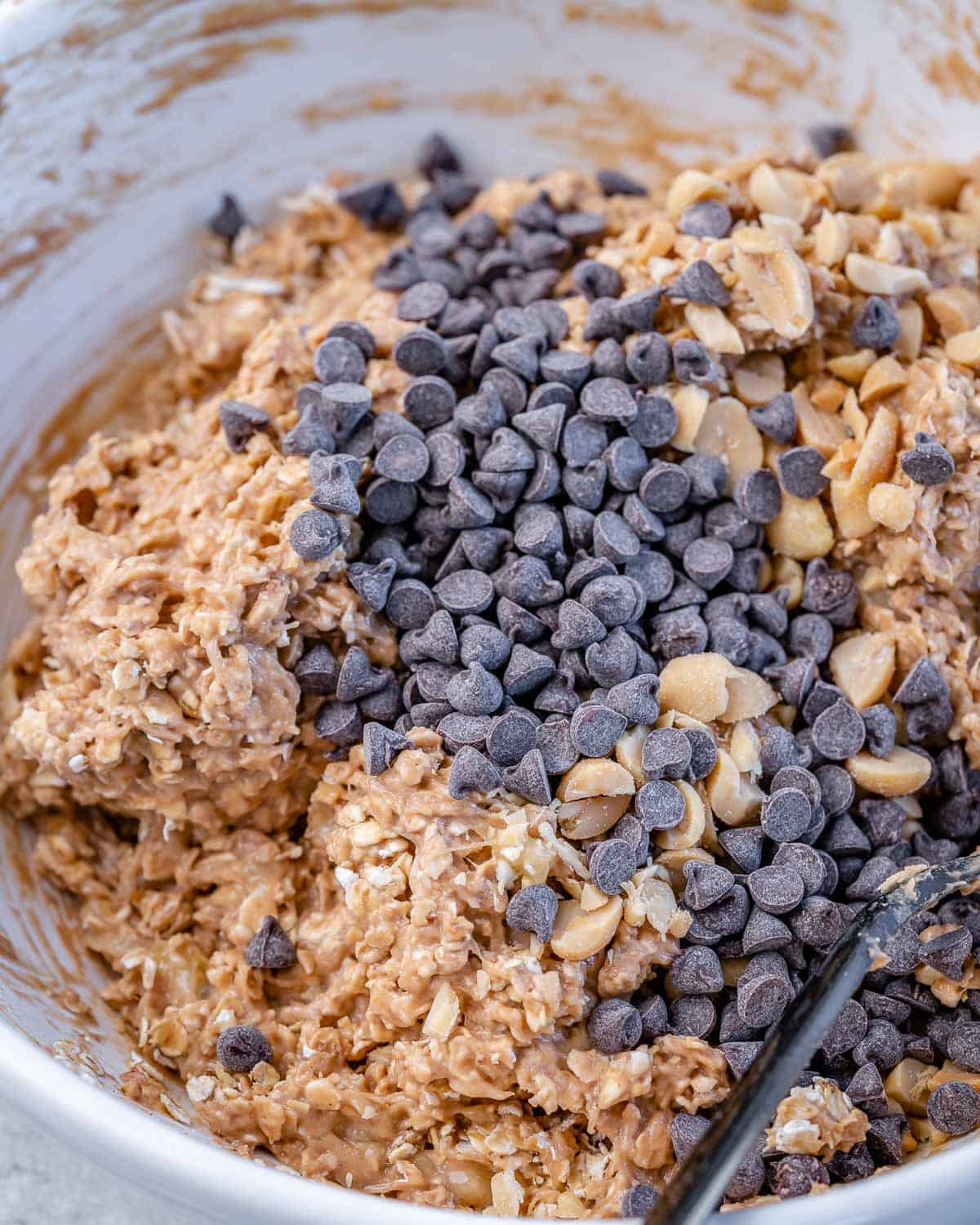 mixing chocolate chips into oat mixture with peanuts and peanut butter