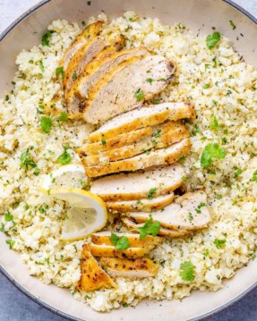 top view cauliflower rice in a skillet with sliced chicken breast