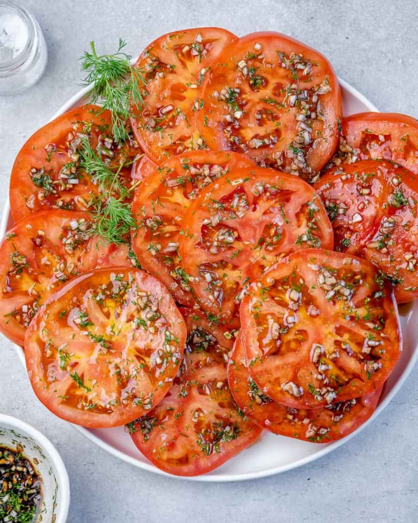 top view of marinated slices of tomatoes on a white plate 