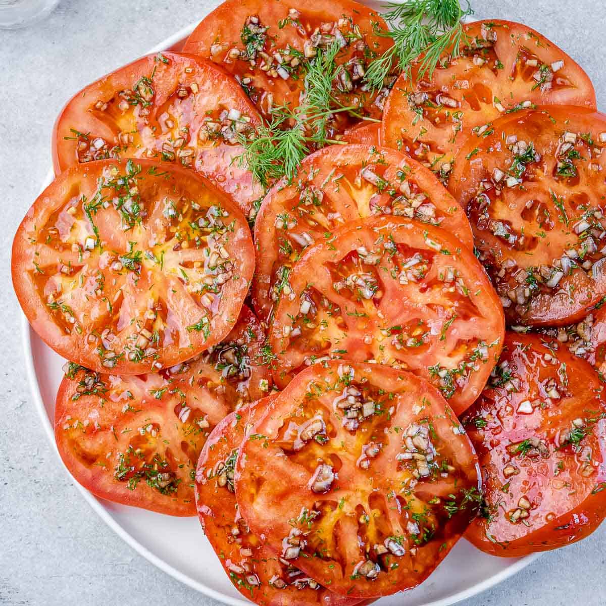 top view marinated sliced tomatoes on a white plate