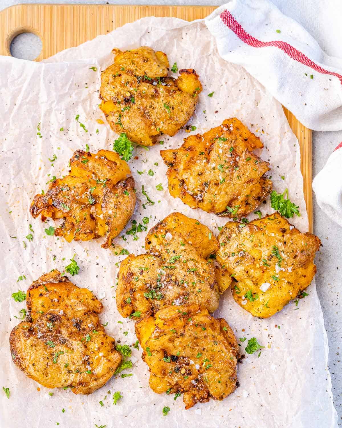 smashed potatoes on parchment paper with herbs and seasoning
