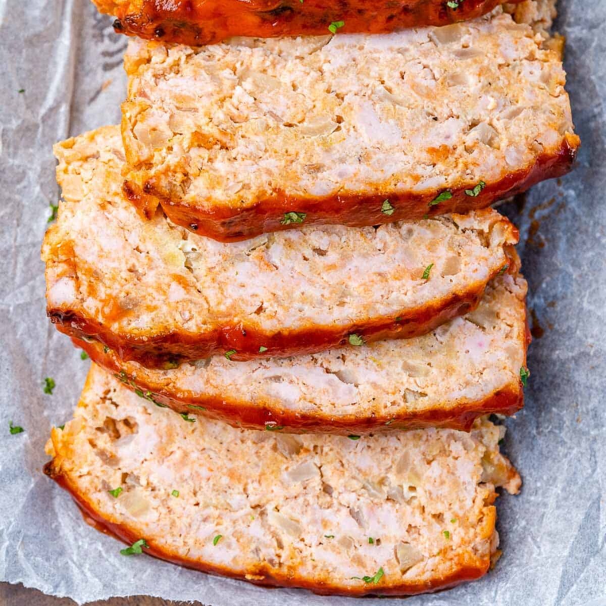 top view sliced meatloaf laid next to one another on parchment paper