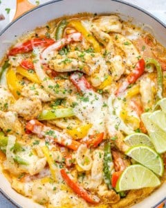 close up fajita chicken in skilet topped with melted cheese and lime wedges