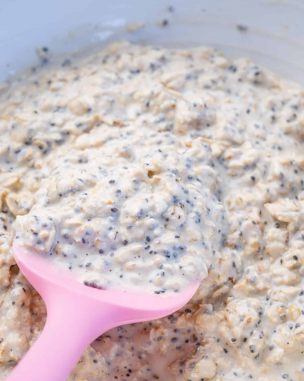 thickened overnight oats in a bowl with pink spatula in it.