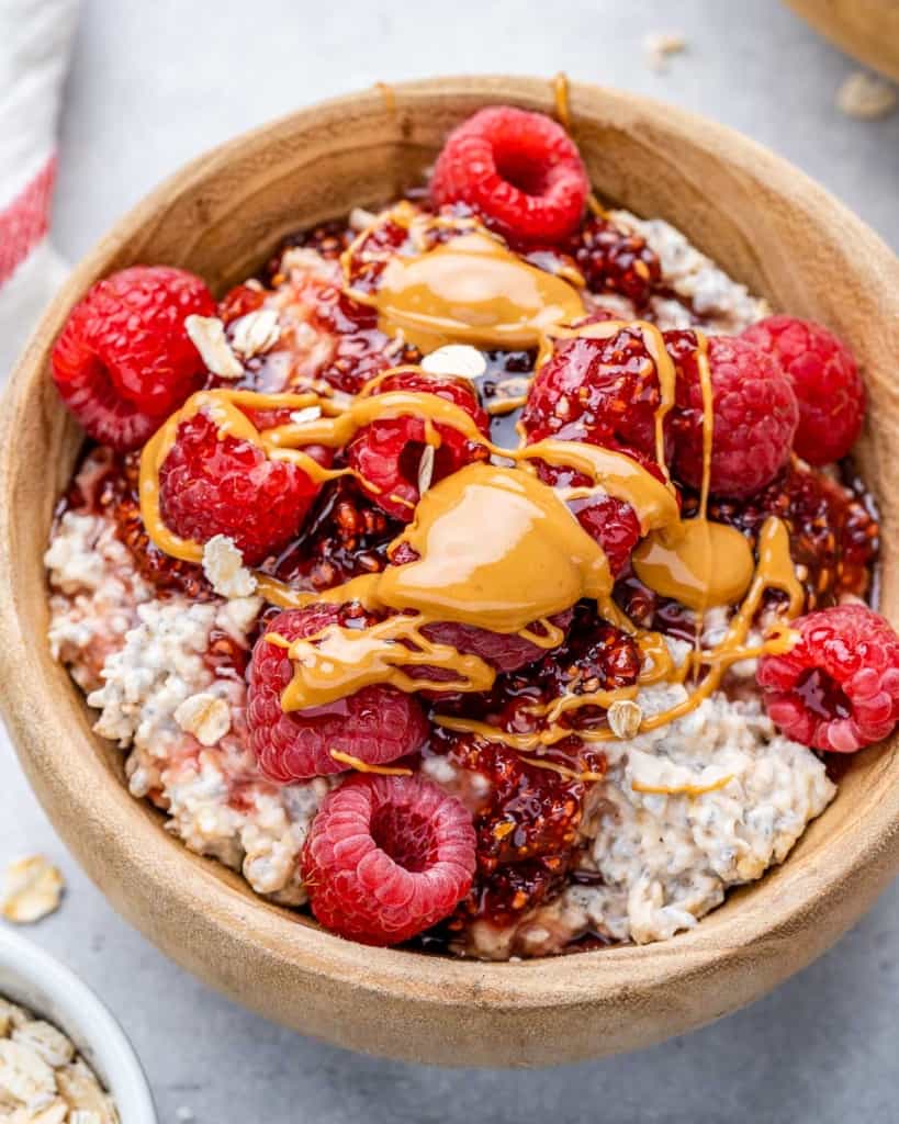 top view overnight oatmeal in a tan bowl topped with raspberry and peanut butter drizzle 