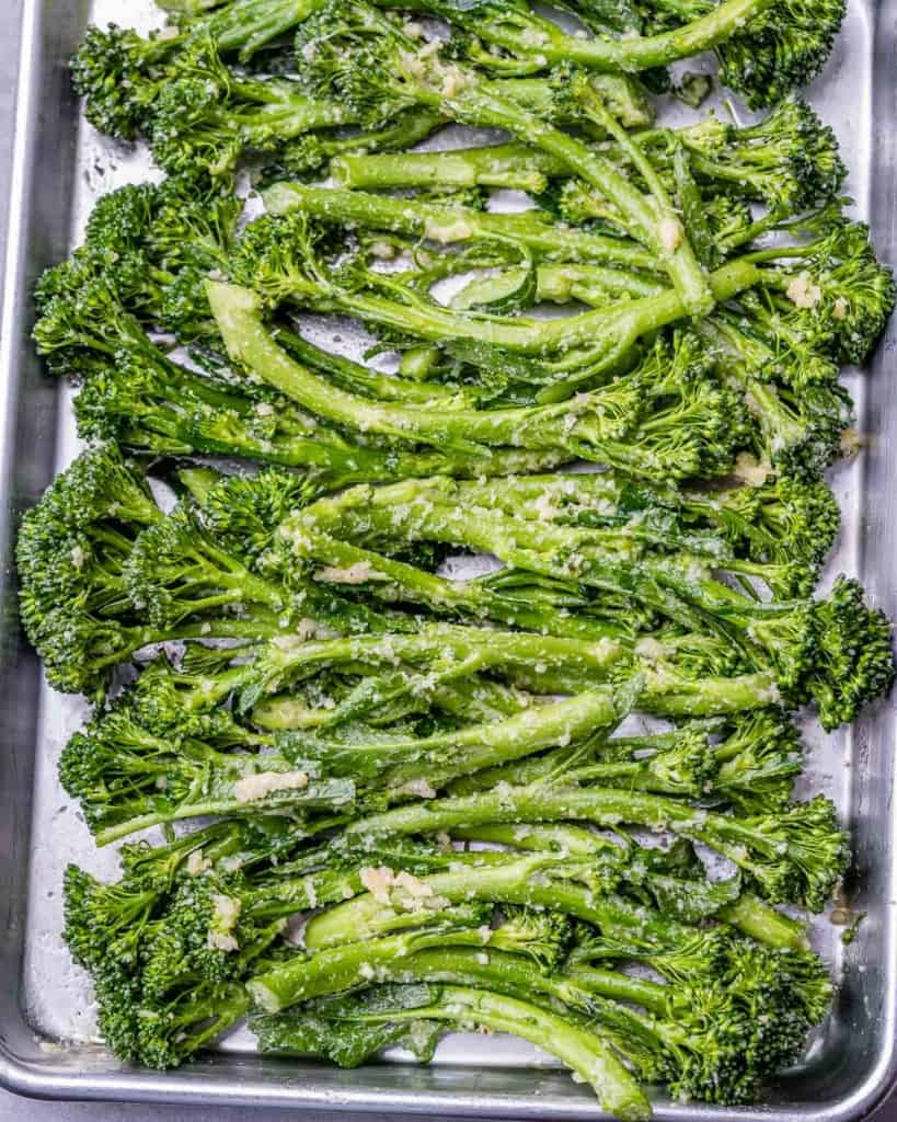 seasoned broccolini added to pan before roasting 