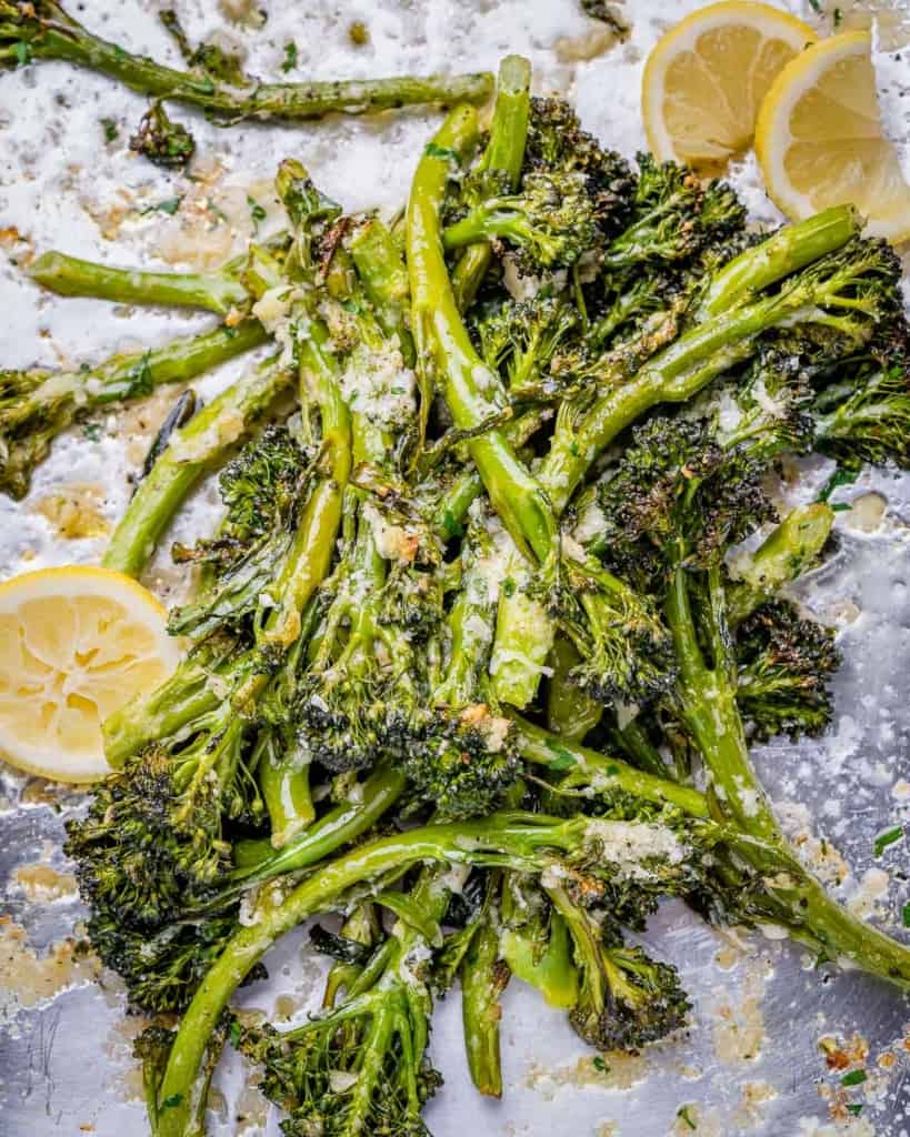 top view roasted broccolini on a pan with lemon garnished and parmesan cheese
