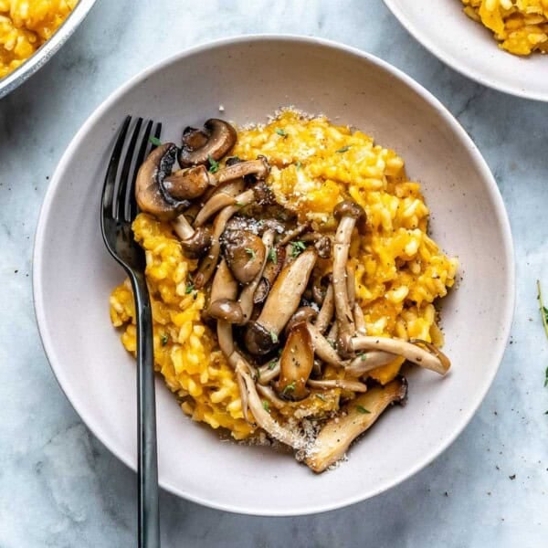 a round bowl with butternut squash risotto topped with sauteed mushrooms.