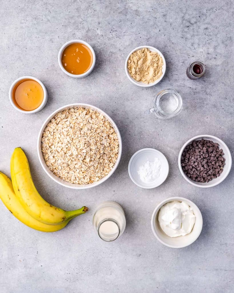 Ingredients to make oatmeal bars on small bowls on a flat gray surface 