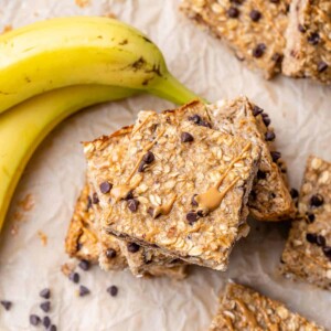 top view of oatmeal bar squares stacked on each other with a banana on the top left corner