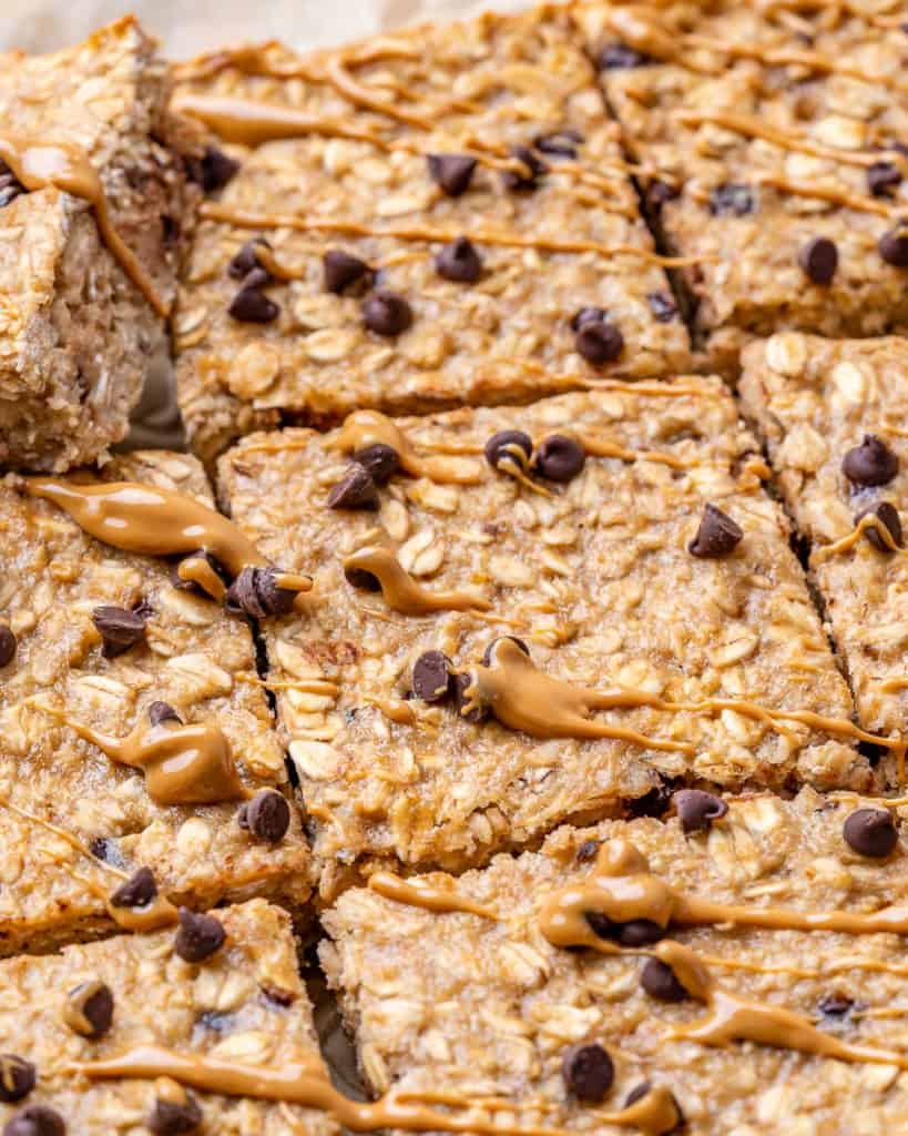 close up image of baked oatmeal chocolate chip bars with peanut butter drizzle over them.