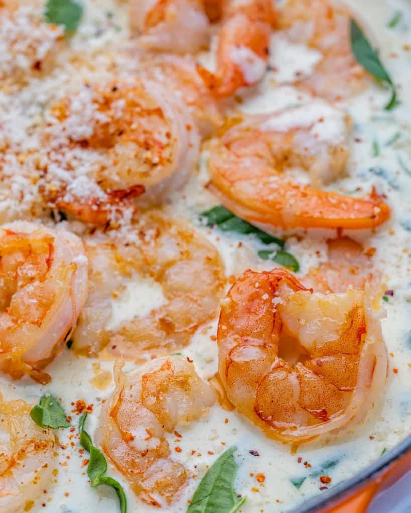 close up sauteed shrimp over a creamy parmesan and spinach sauce 