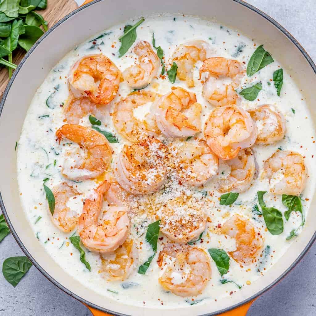 top view shrimp in a creamy spinach sauce in an orange skillet