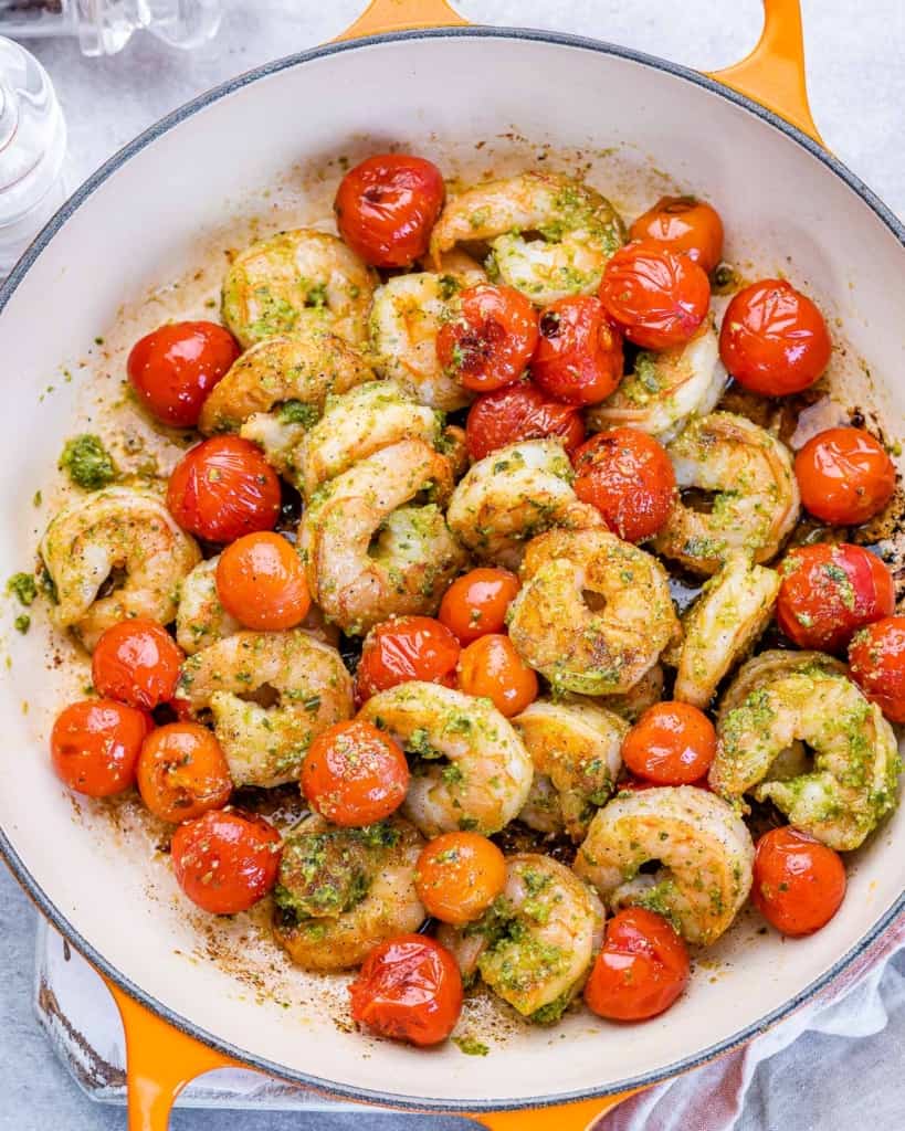 top view sauteed shrimp with tomatoes in an orange skillet