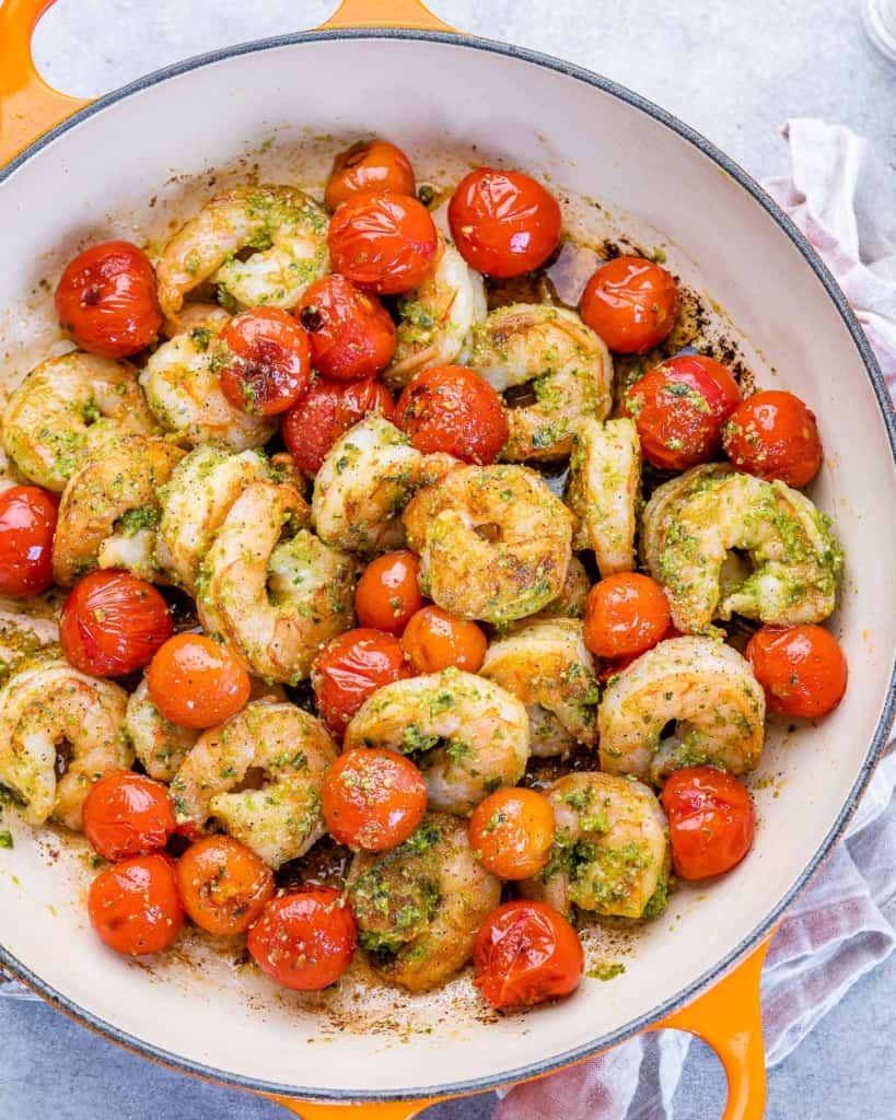 shrimp and tomatoes sauteed in an orange and white skillet