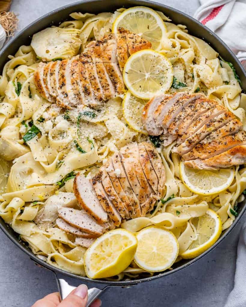 tope view pasta dish in a black skillet topped with sliced lemon chicken breasts