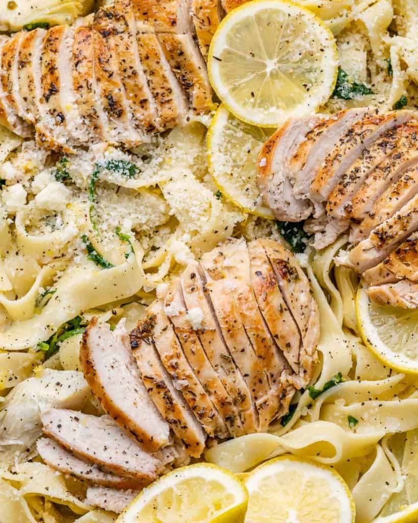 close up view of sliced chicken breast over fettuccine pasta 