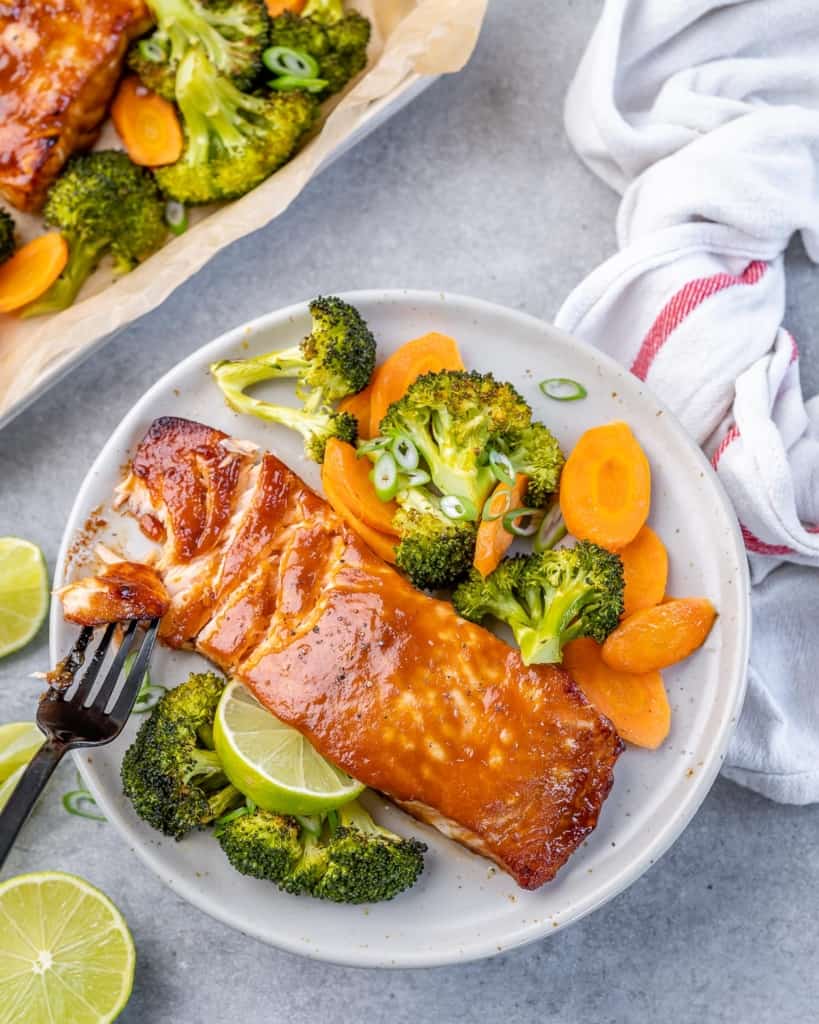 top view of miso salmon on a white plate with broccoli and carrots 