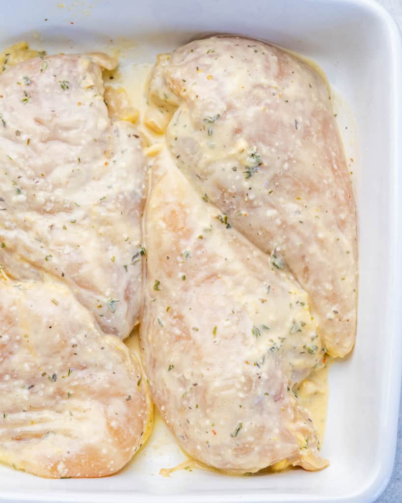 chicken breast in  a shite baking dish with marinade 