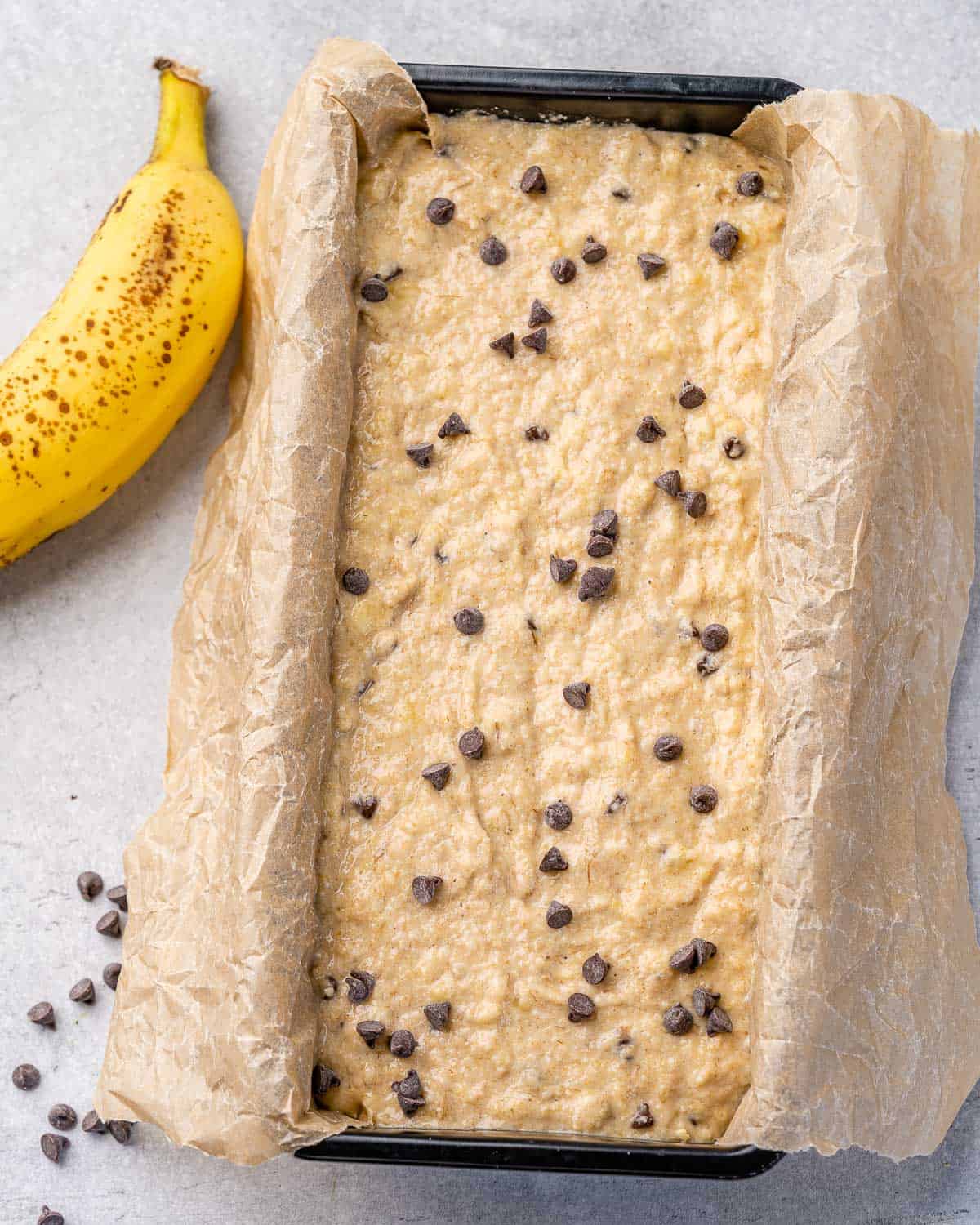 banana bread batter in loaf pan with parchment paper and chocolate chips