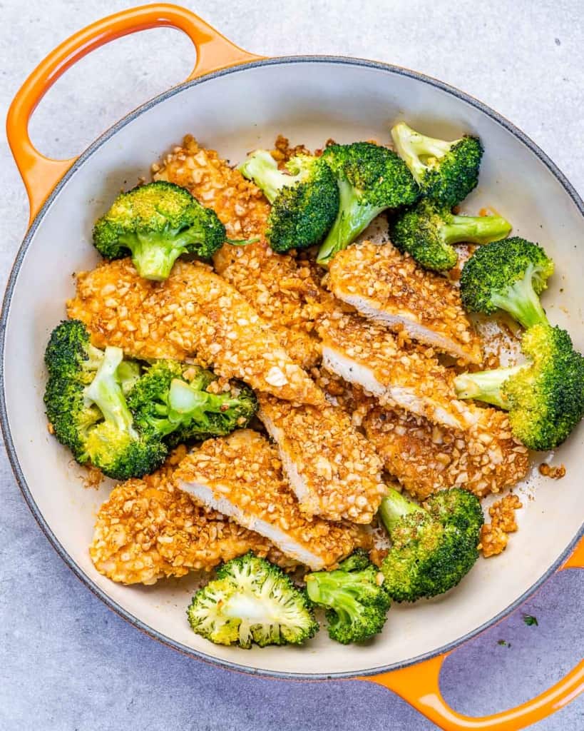 top view chicken breast sliced with side of broccoli in an orange skillet