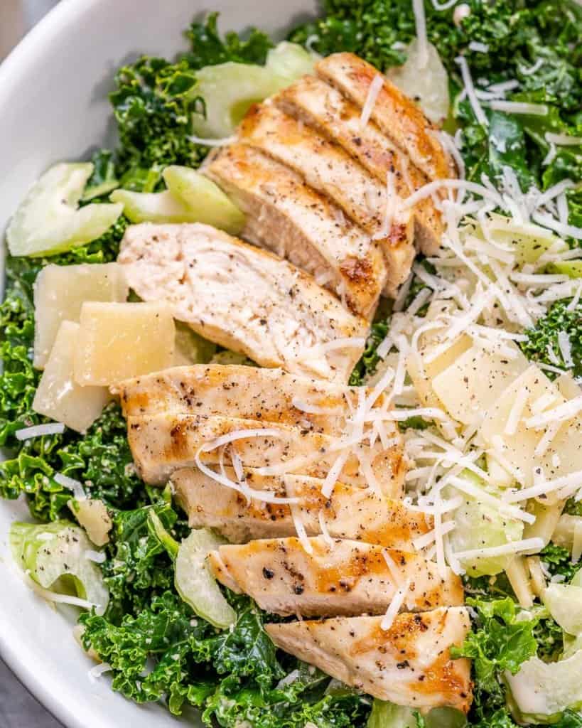 top view chicken kale salad in a bowl topped with parmesan cheese 