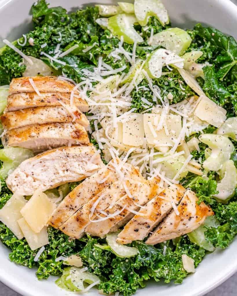 top view kale salad with chicken in a white bowl