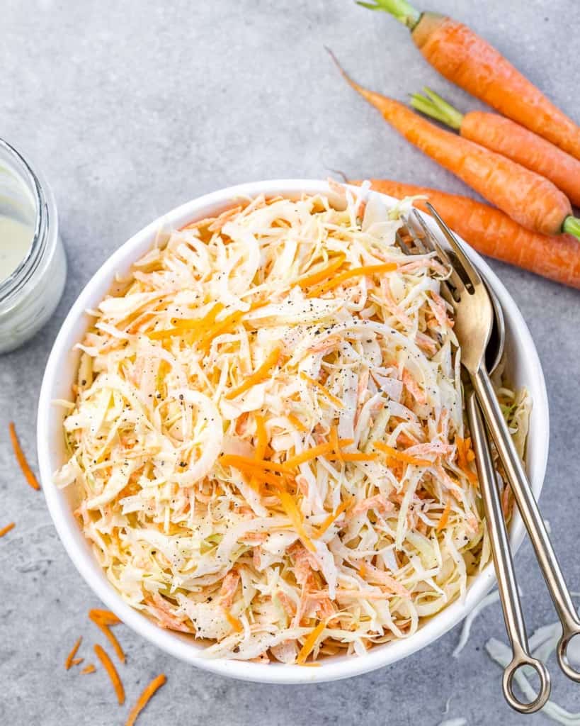 top view of healthy coleslaw in a bowl with utensils in bowl
