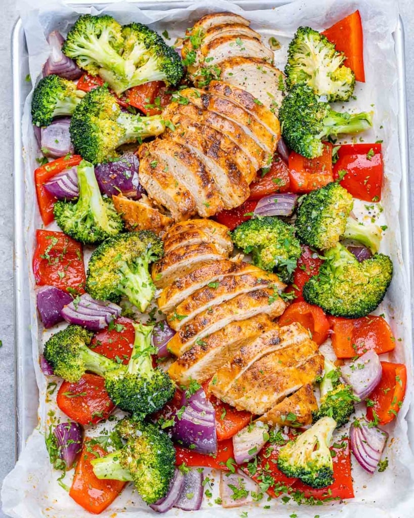 top view sliced baked chicken breast with veggies on a sheet pan
