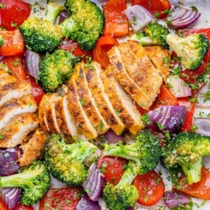 top view sliced chicken breast on a sheet pan with roasted broccoli onions and red peppers