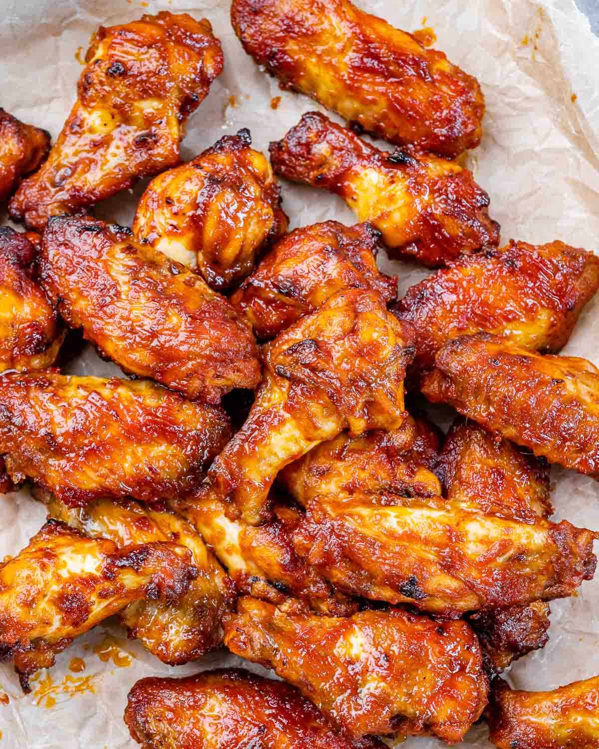 close up of buffalo wings on parchment paper. 