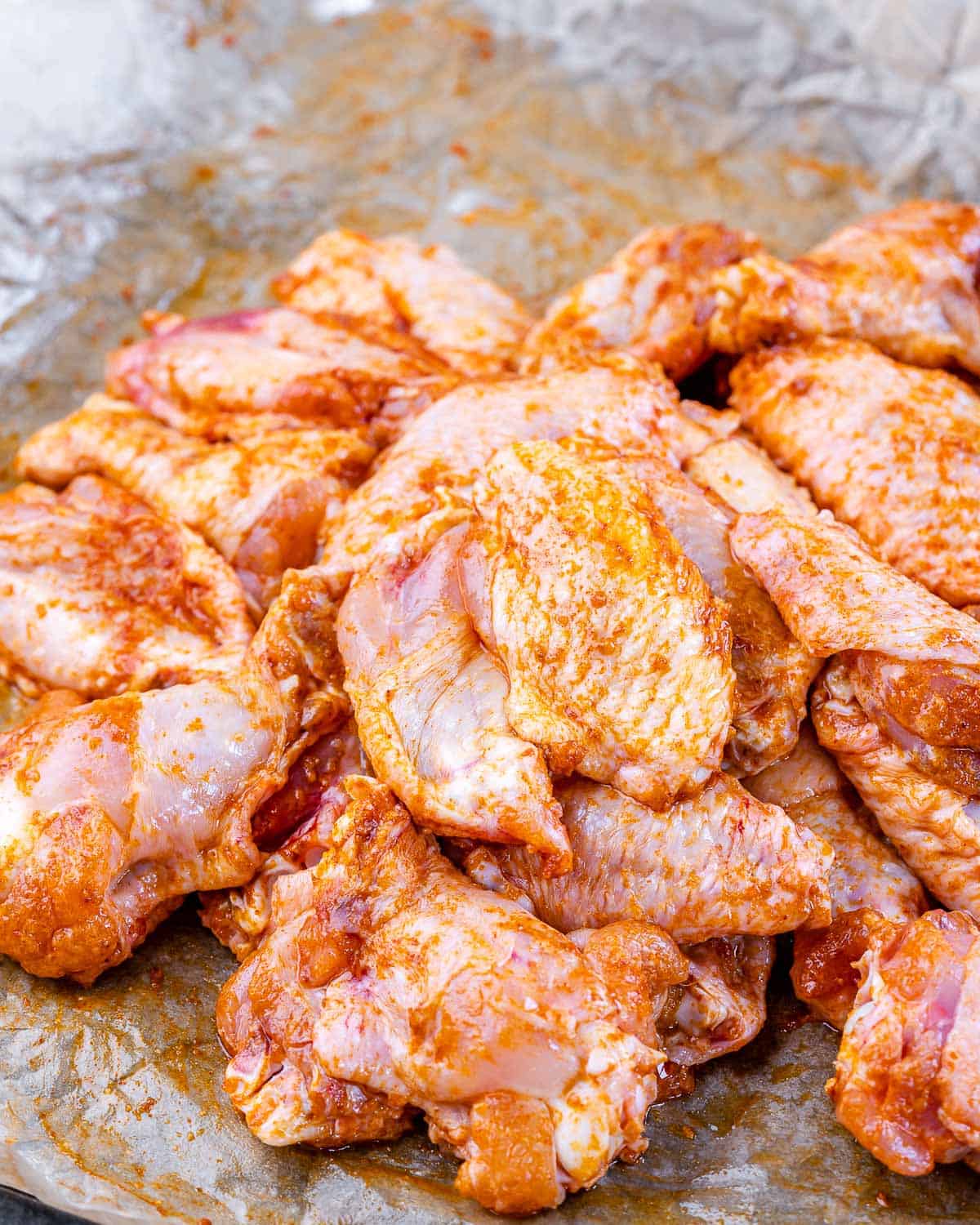 coating wings with seasoning mix on parchment paper 
