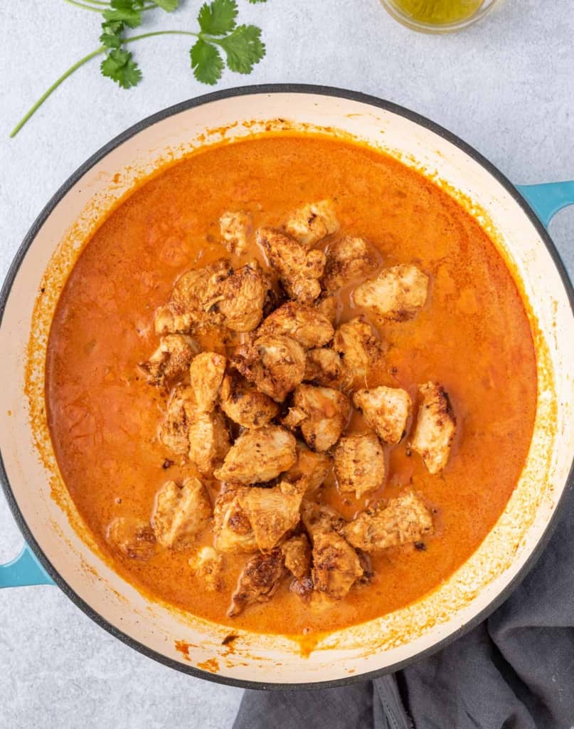 chicken poured into the pot of creamy tikka sauce 