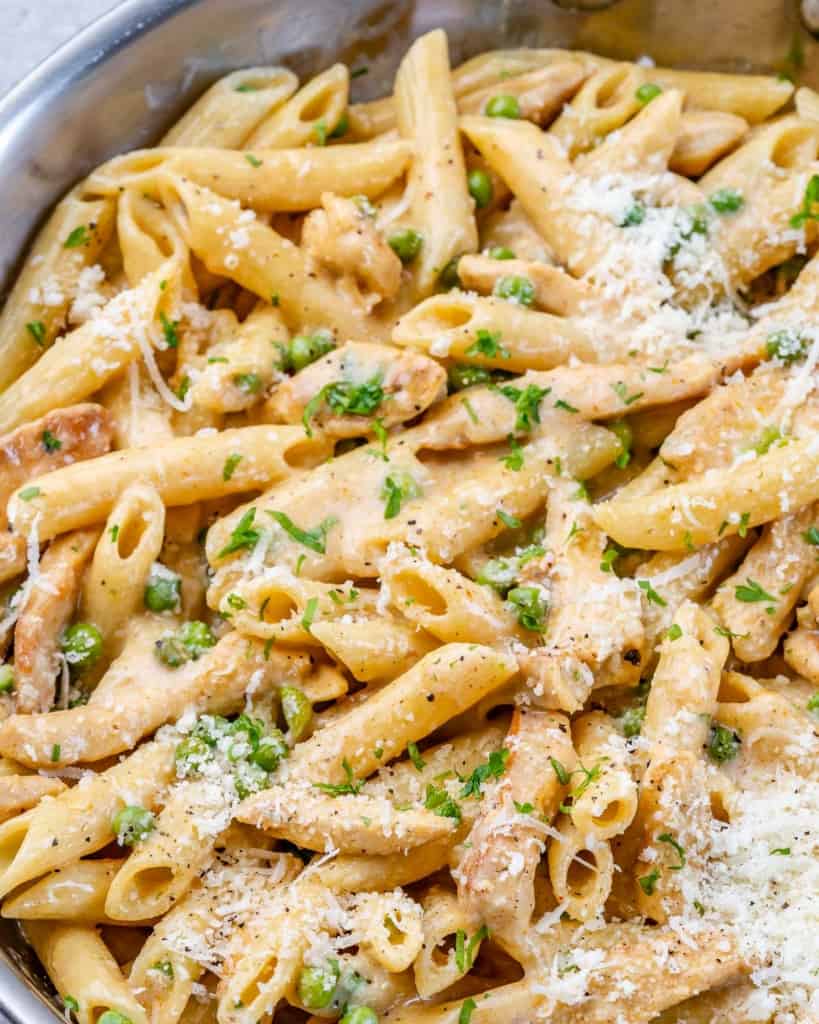 close up chicken and pasta with peas and topped with parmesan cheese