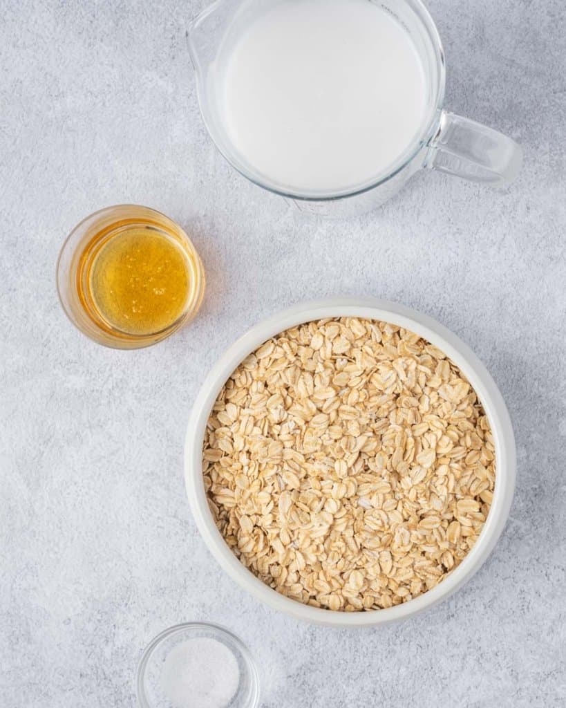 ingredients to make oatmeal breakfast bowl. rolled oats, milk, maple syrup and salt
