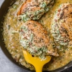 yellow spatula lifting up a stuffed chicken breast from skillet