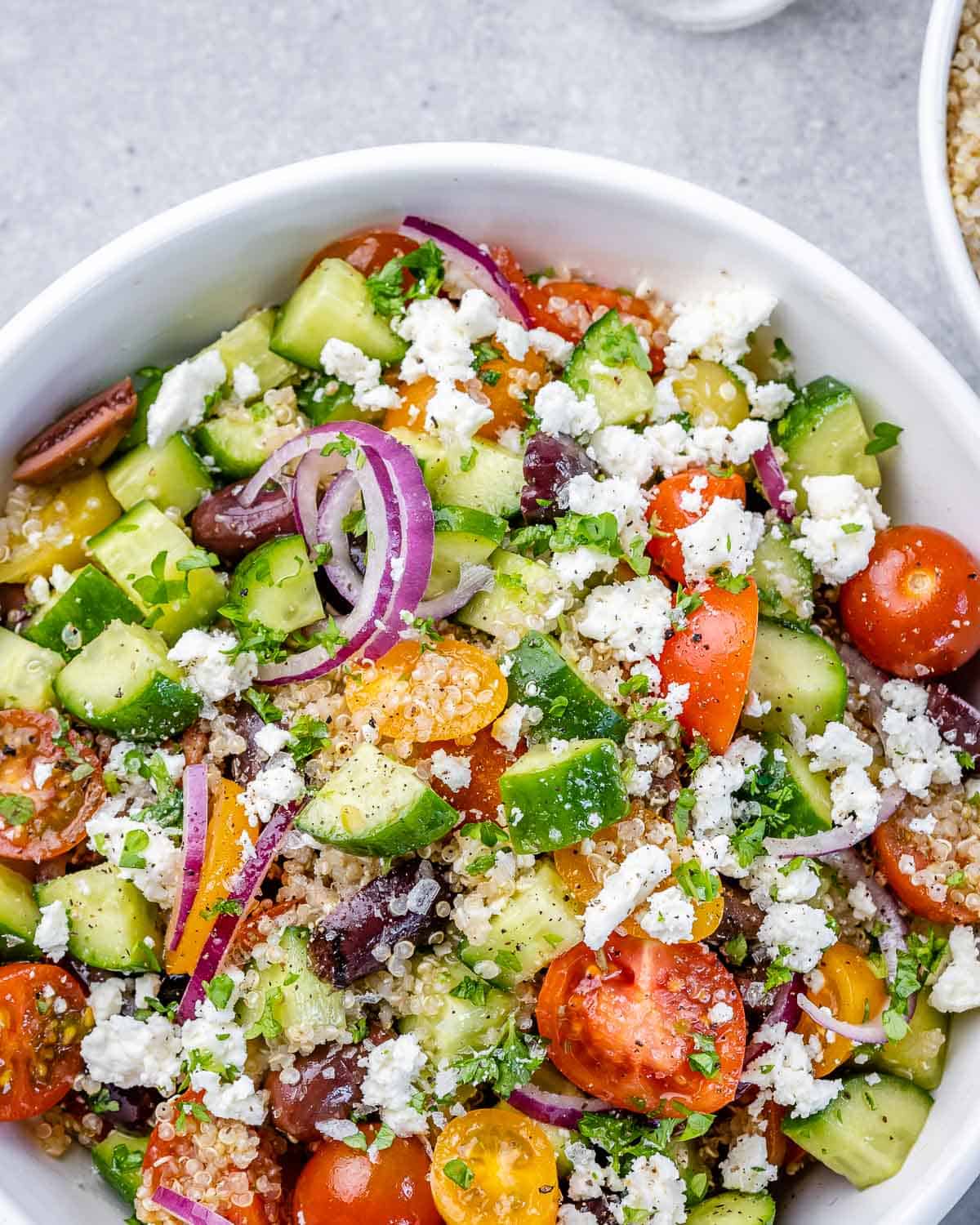 Close up of Mediterranean quinoa salad in circular white serving bowl. 