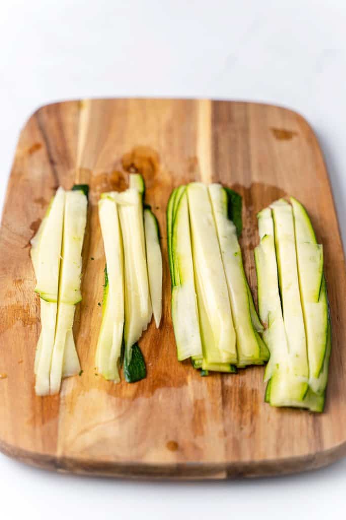 layers of zucchini cut into noodles on a cutting board