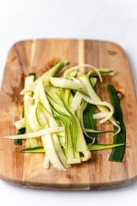 thin cut zoodles on a cutting board