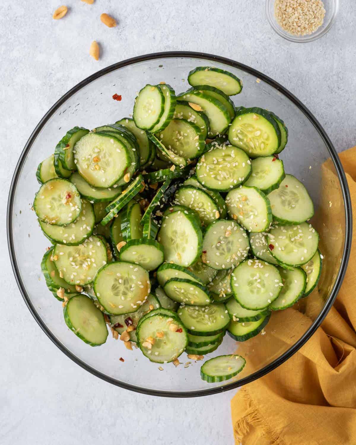 cucumber tossed in with dressing in a clear round bowl.