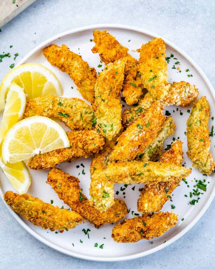 close up of crispy baked avocado fries on a white plate 