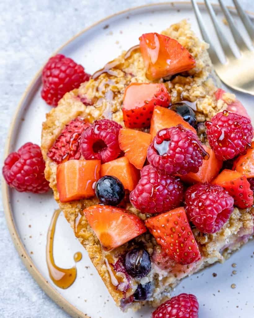 top view of slice of baked oatmeal topped with fresh berries and maple syrup.