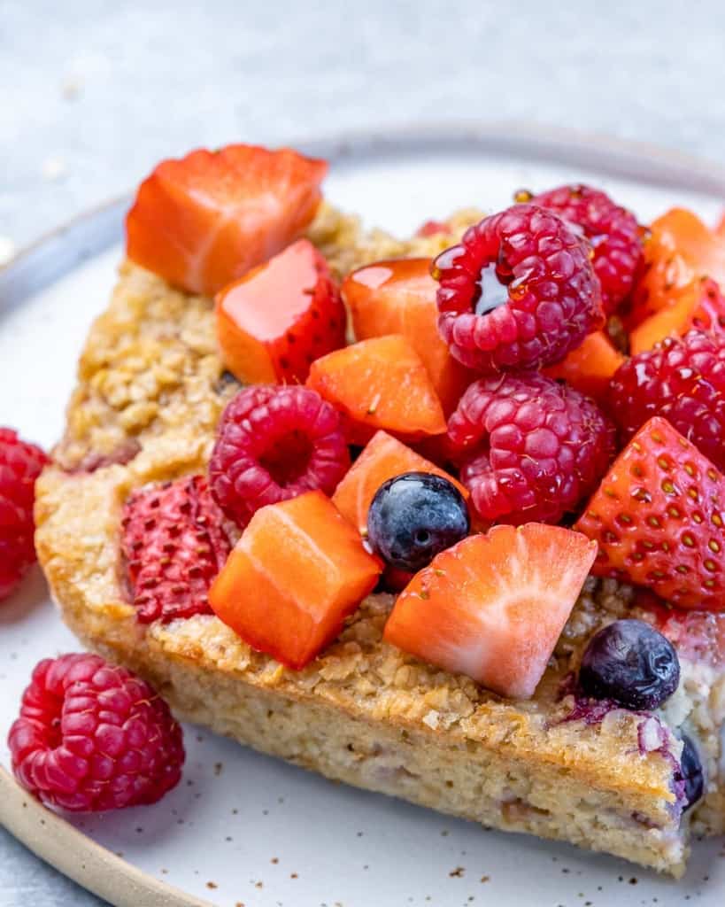 side shot of baked oatmeal slice topped with berries on a plate 