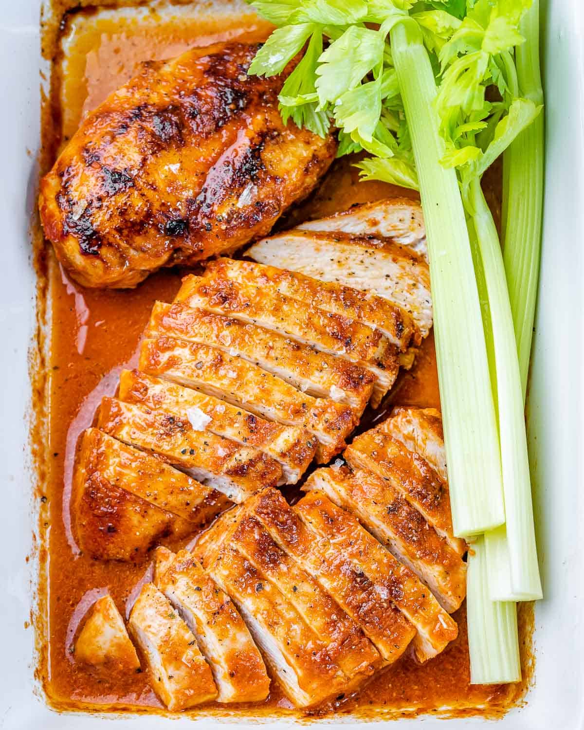 top view of sliced buffalo chicken breasts in dish with celery 