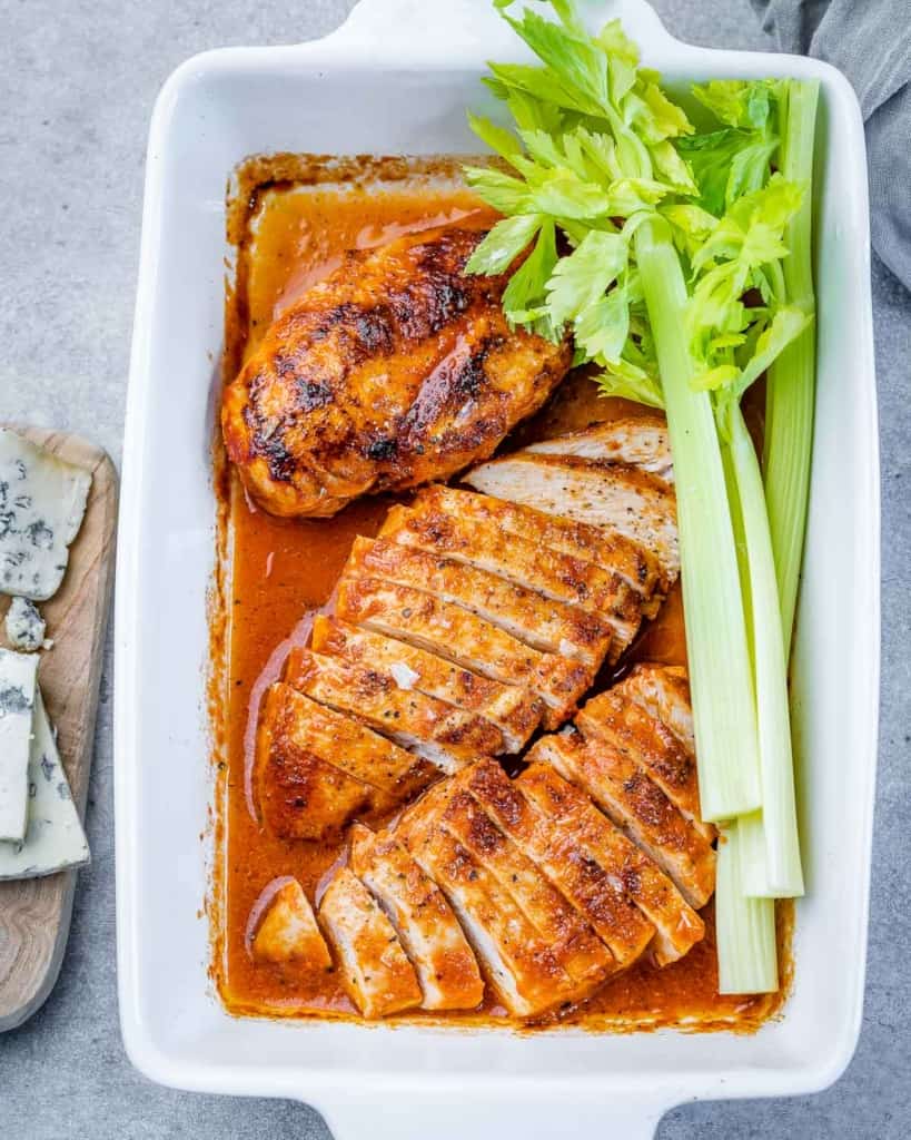 three buffalo chicken breasts in dish with celery