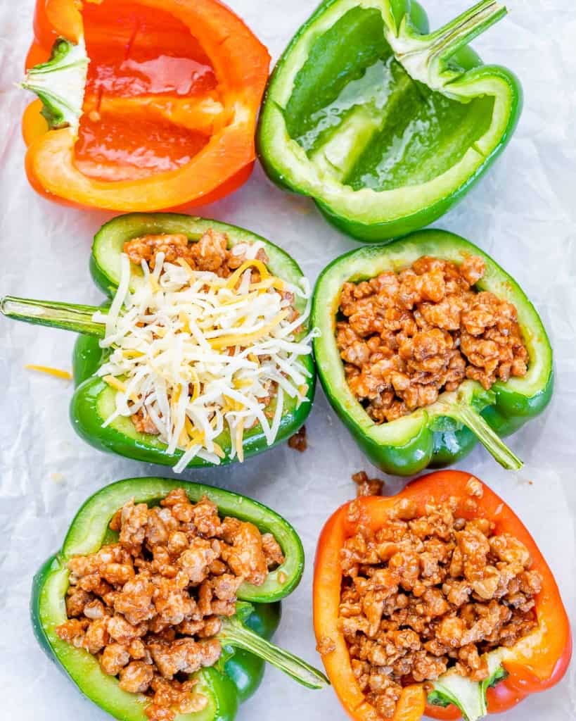 Stuffing peppers with ground meat and sprinkling cheese.