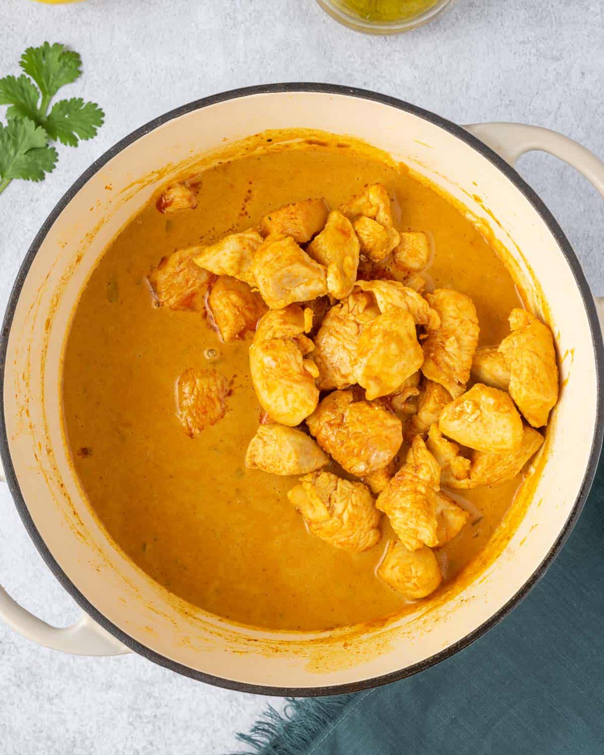 chicken added over curry sauce in a pot